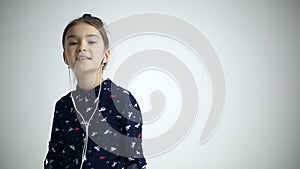 Child uses smartphone with earflaps at studio background.