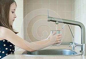 Child using filter to purify drinking clean water. Kitchen faucet. Filling cup beverage. Infection viruses through tap water.