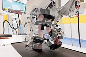 Child using robotic gait trainer for walking therapy on a treadmill at pediatric rehabilitation clinic photo