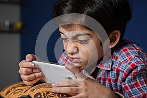 Child using a smart-phone with funny expression.