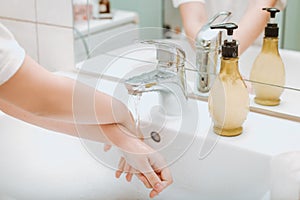 Child using soap and washing hands under the water tap.