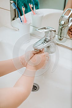 Child using soap and washing hands under the water tap