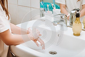 Child using soap and washing hands under the water tap