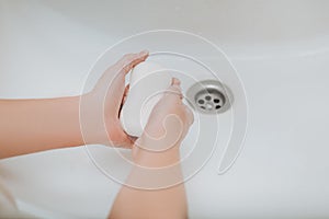 Child using soap and washing hands under the water tap.