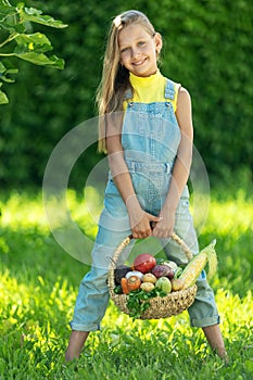 Child with vegetables. Happy little girl holding vegetables in her hands.