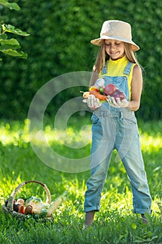 Child with vegetables. Happy little girl holding vegetables in her hands.