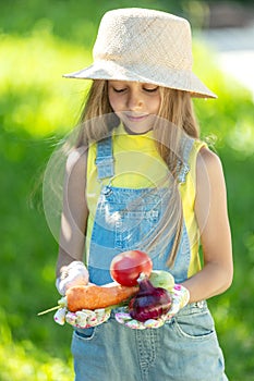 Child with vegetables. Happy little girl holding vegetables in her hands.