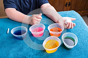 Child waiting for dye tablets to dissolve for easter egg dyeing