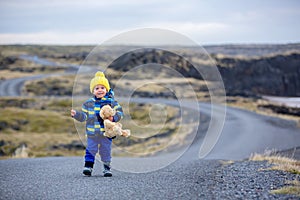 Child, walking on a curved road near ocean in beautiful nature in Snaefellsjokull National Park in Iceland, autumntime on sunset