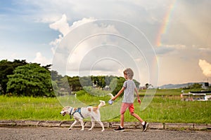 Child walking dog. Kid and pet watch rainbow
