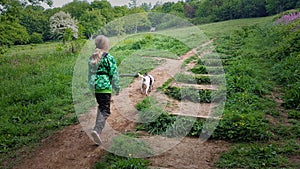 Child walking a dog though a wooded meadow Devon uk