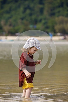 Child walking on fine sand through the water