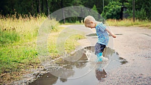 Child walking in wellies in puddle on rainy weather