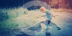 Child walking in wellies in puddle on rainy weather