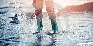 Child walking in wellies in puddle on rainy weather