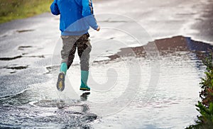 Child walking in wellies in puddle on rainy weather