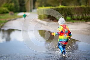 Child walking in wellies in puddle on rainy weather