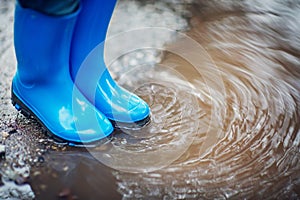 Child walking in wellies in puddle on rainy weather