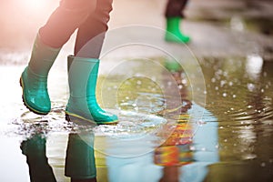 Child walking in wellies in puddle on rainy weather