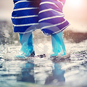 Child walking in wellies in puddle on rainy weather