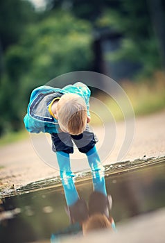 Child walking in wellies in puddle on rainy weather