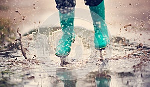 Child walking in wellies in puddle on rainy weather photo