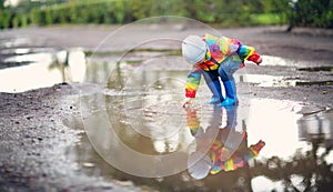 Child walking in wellies in puddle on rainy weather photo