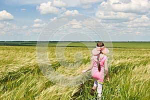 Child walking through the wheat field, bright sun, beautiful summer landscape