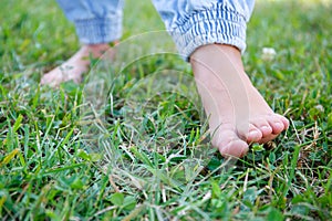 The child walks barefoot on the grass