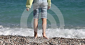 Child walks on seashore and wets feet