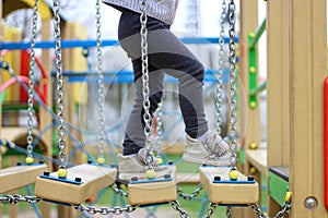 child walks on a suspended children& x27;s chain road on the playground