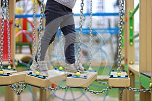 child walks on a suspended children& x27;s chain road on the playground