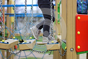 child walks on a suspended children& x27;s chain road on the playground