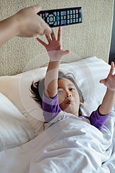 Asian Child On Bed Wants to Take Over Television Remote Control from His Parent Hands. Addiction or Parental Advisory Concept photo