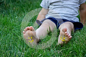 The child was lying on the green grass. Smile with paints on the legs and arms. Child having fun outdoors in the spring