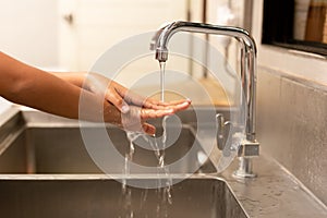 Child washing hands with liquid soap under the tap water