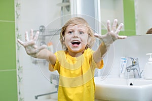 Child washing hands and showing soapy palms