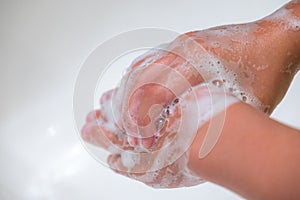 A child washing his hands with soap in bathroom sink