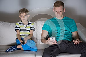 Child watching tv and dad using phone