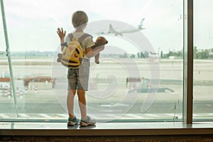Child, watching from the window of the airport the planes, taking off and landing while waiting at to board the aircraft
