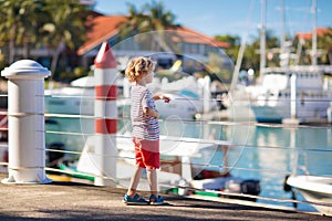 Child watching yacht and boat in harbor. Yachting