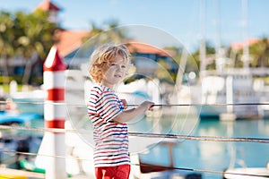 Child watching yacht and boat in harbor. Yachting