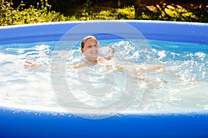 A child in the water. A girl splashes in an inflatable pool in the garden on a sunny summer day