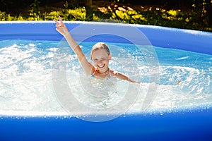 A child in the water. A girl splashes in an inflatable pool in the garden on a sunny summer day