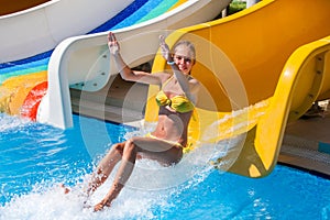 Child on water slide at aquapark jump .