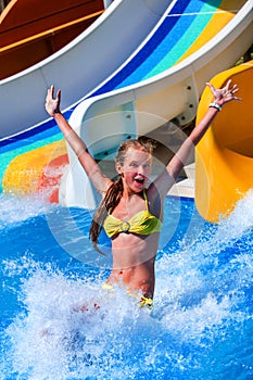 Child on water slide at aquapark show thumb up.