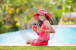 Child with watermelon in swimming pool