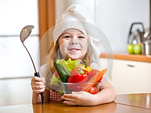 Child weared as cook with vegetables at kitchen