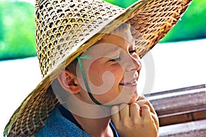 Child is wearing a hat made of bamboo during a boattrip