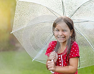 Child with wearing polka dots dress under umbrella